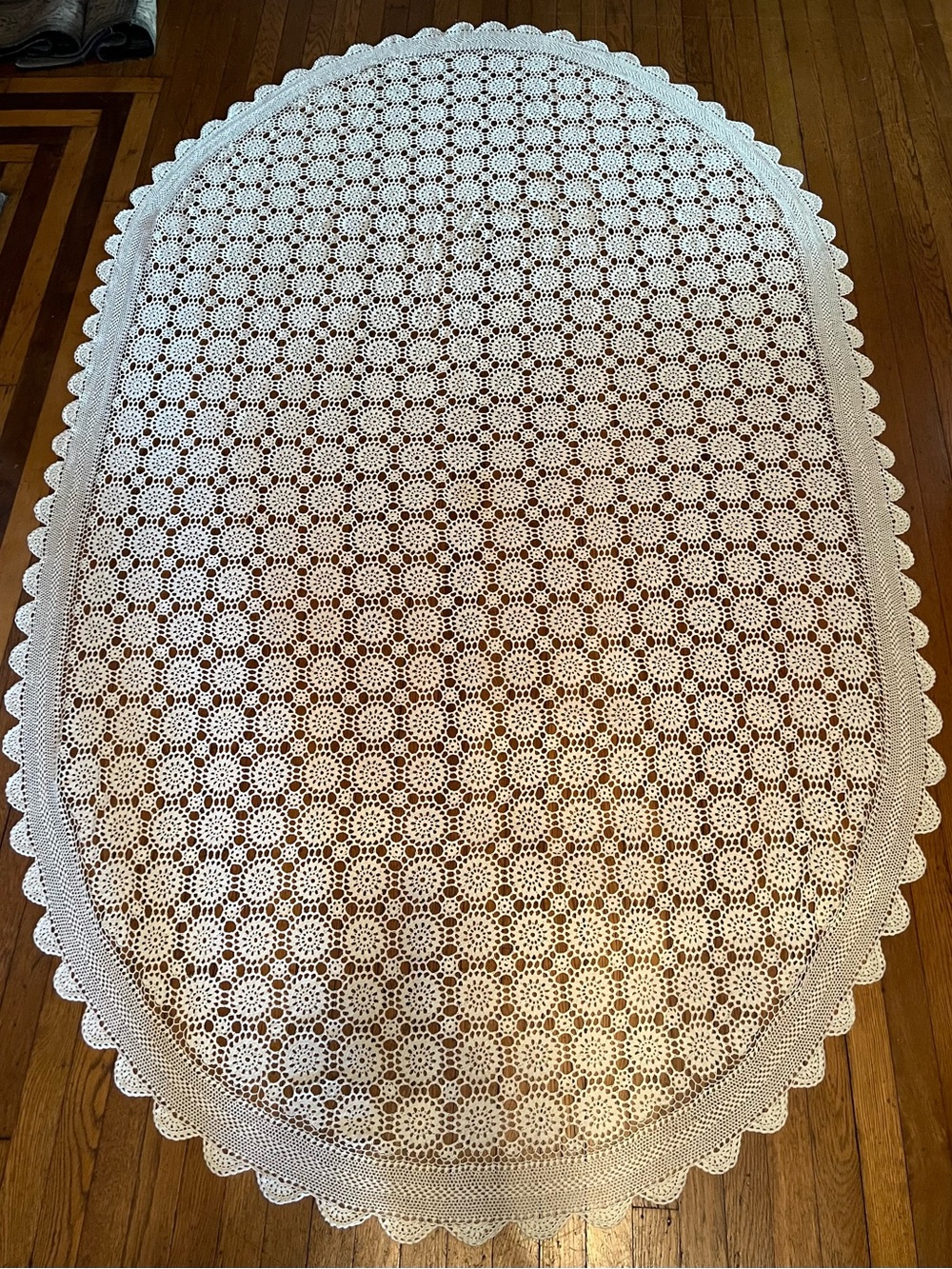 Hand crocheted, oval ivory tablecloth with scalloped edge 56 width by 94 length.